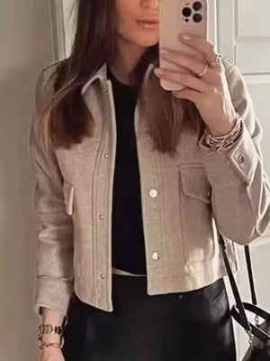 Beige trucker jacket with snap buttons, chest pockets, and buttoned cuffs.