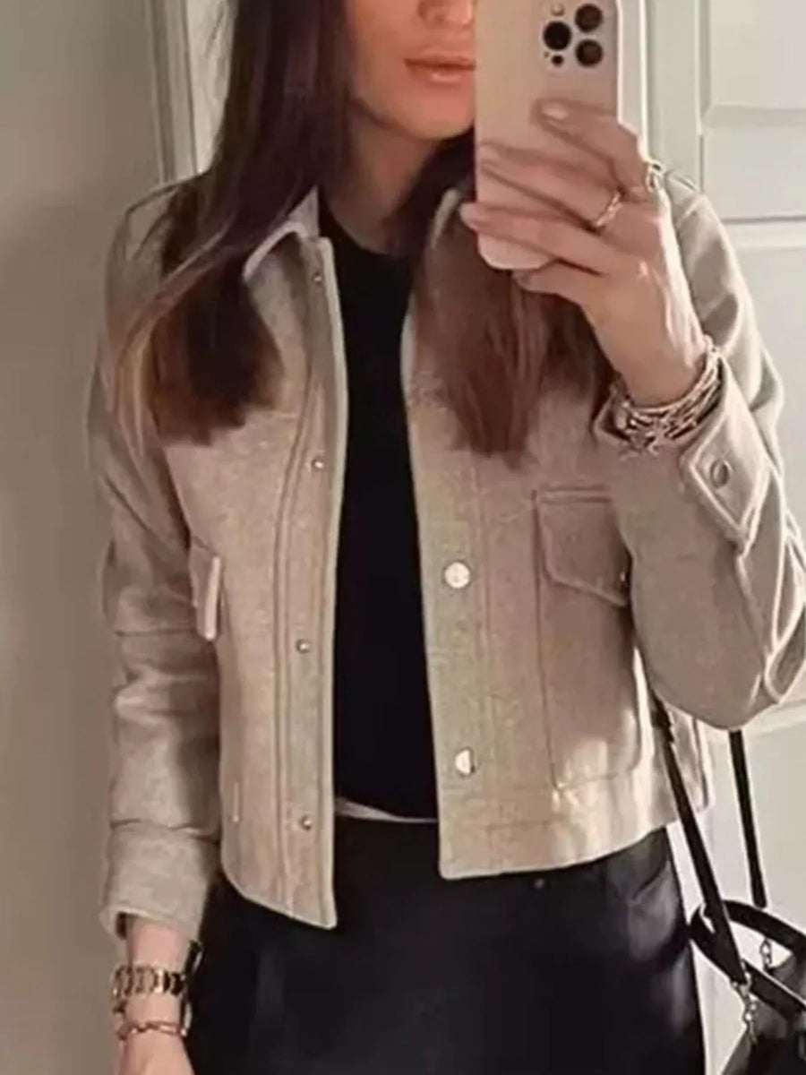 Beige trucker jacket with snap buttons, chest pockets, and buttoned cuffs.