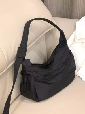 Black nylon crossbody bag with adjustable strap and exterior pockets