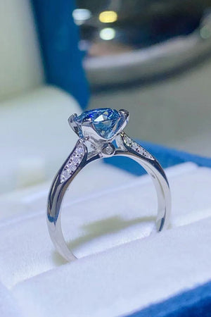 Celestial blue moissanite engagement ring with diamond accents on band.