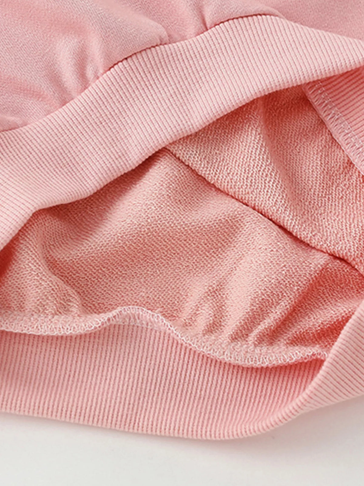 Pale blush cotton crew neck sweatshirt detail showing soft brushed interior fabric.