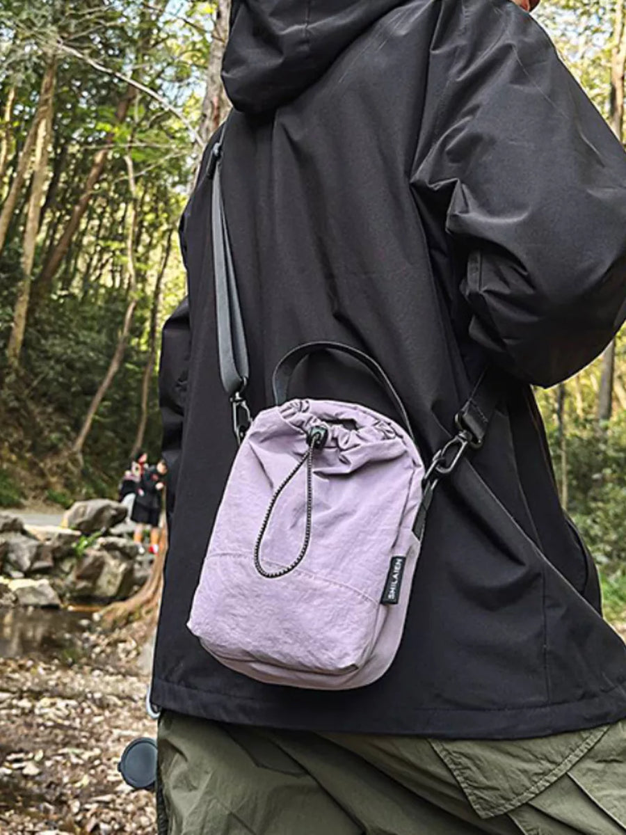 Mini nylon drawstring shoulder bag in purple with adjustable strap and top handle.