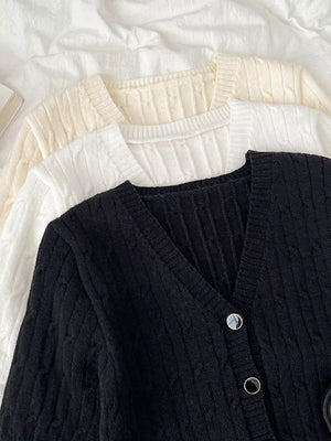 Black cable-knit cropped cardigan with V-neck and button details.