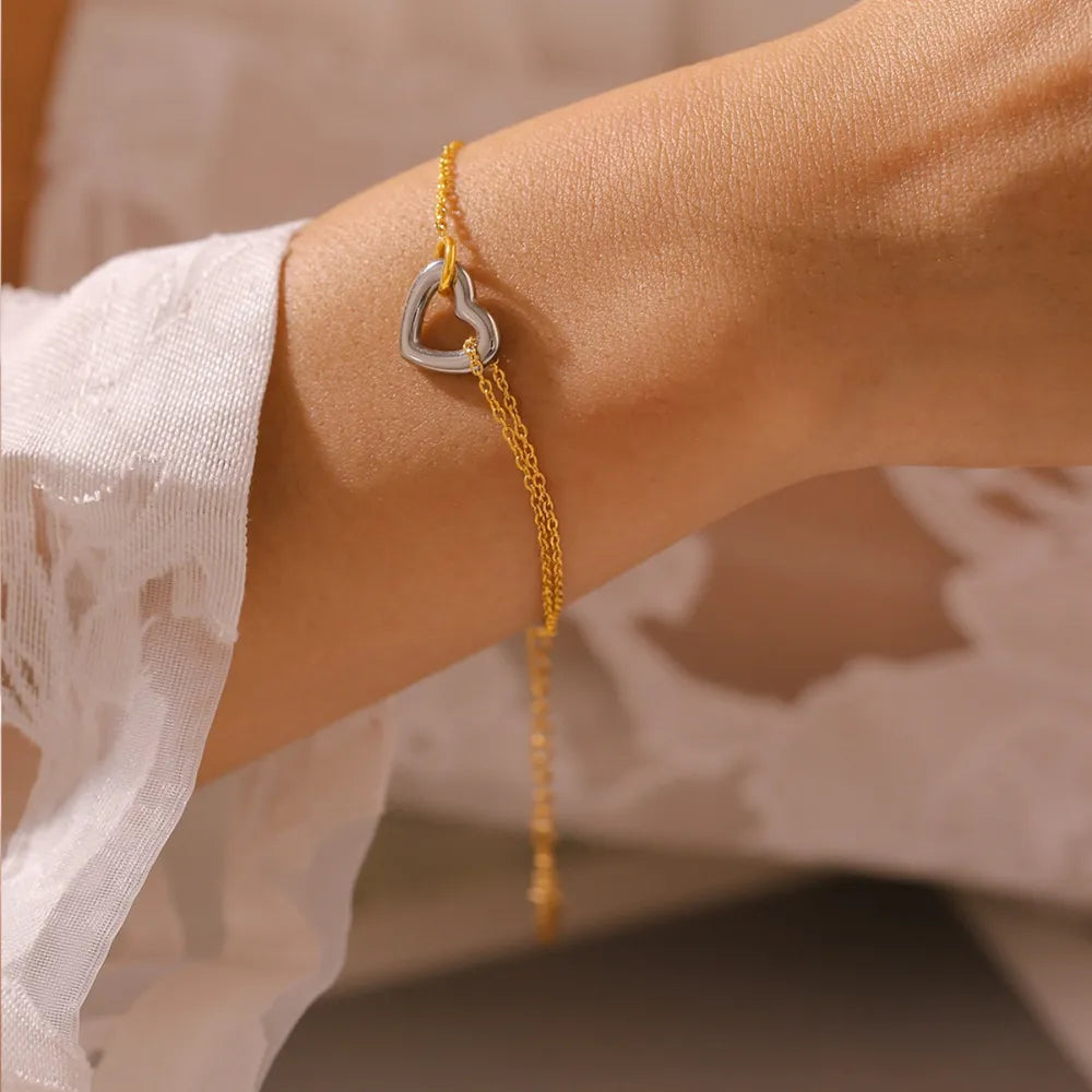 Two-tone heart charm bracelet with a delicate gold chain.
