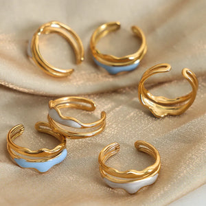 Sculpted enamel wave rings in gold with light blue and white accents.