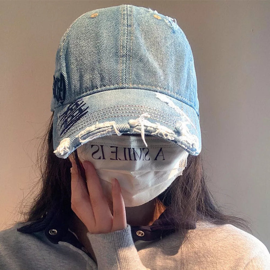 Denim baseball cap with distressed details and dark embroidery.