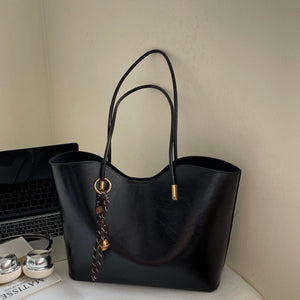 Black pu leather large tote bag with decorative tassel and bell charm.