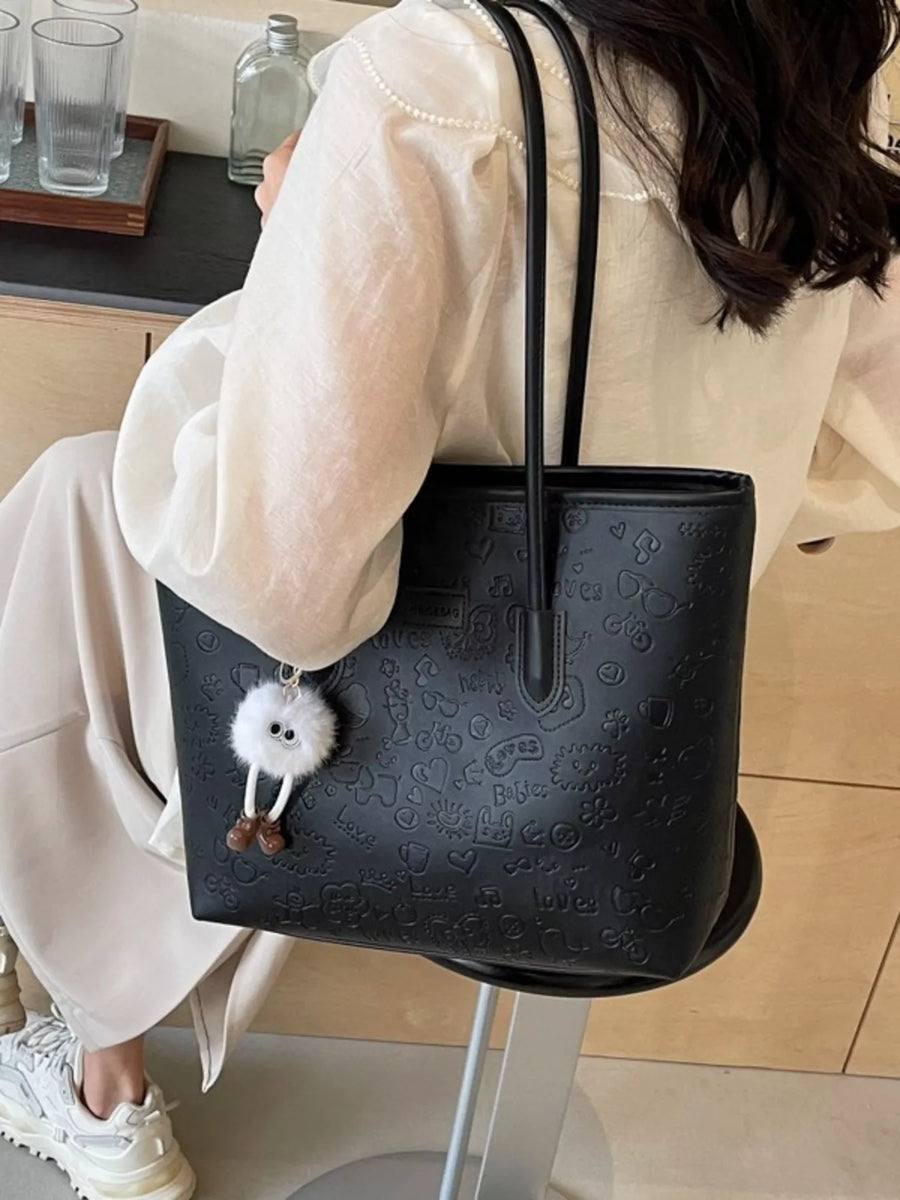 Black embossed PU leather tote bag with cartoon pattern and fluffy keychain.