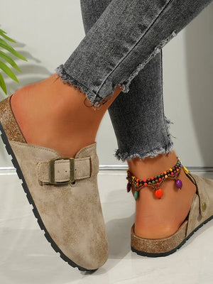 Beige suede mules with buckle detail and cork sole, styled with distressed jeans.