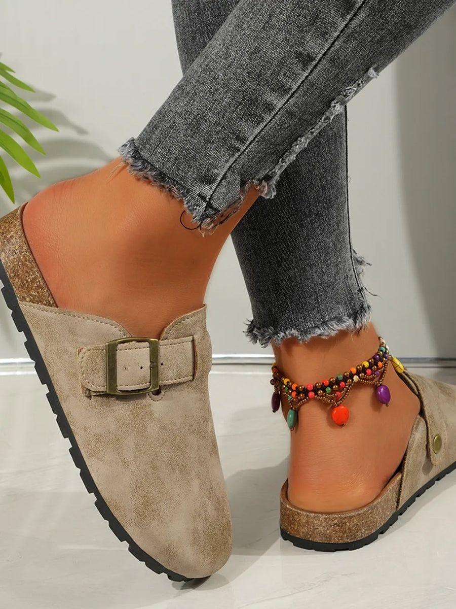 Beige suede mules with buckle detail and cork sole, styled with distressed jeans.