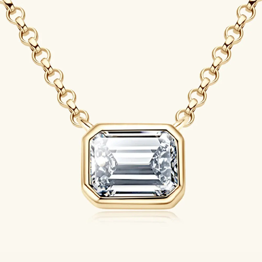 Gold bezel necklace with emerald cut moissanite pendant on a link chain.