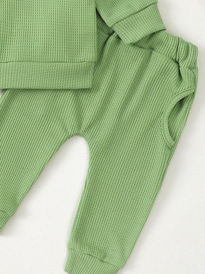 Green waffle knit toddler top and pants set with cuffed sleeves and elastic waist pants.