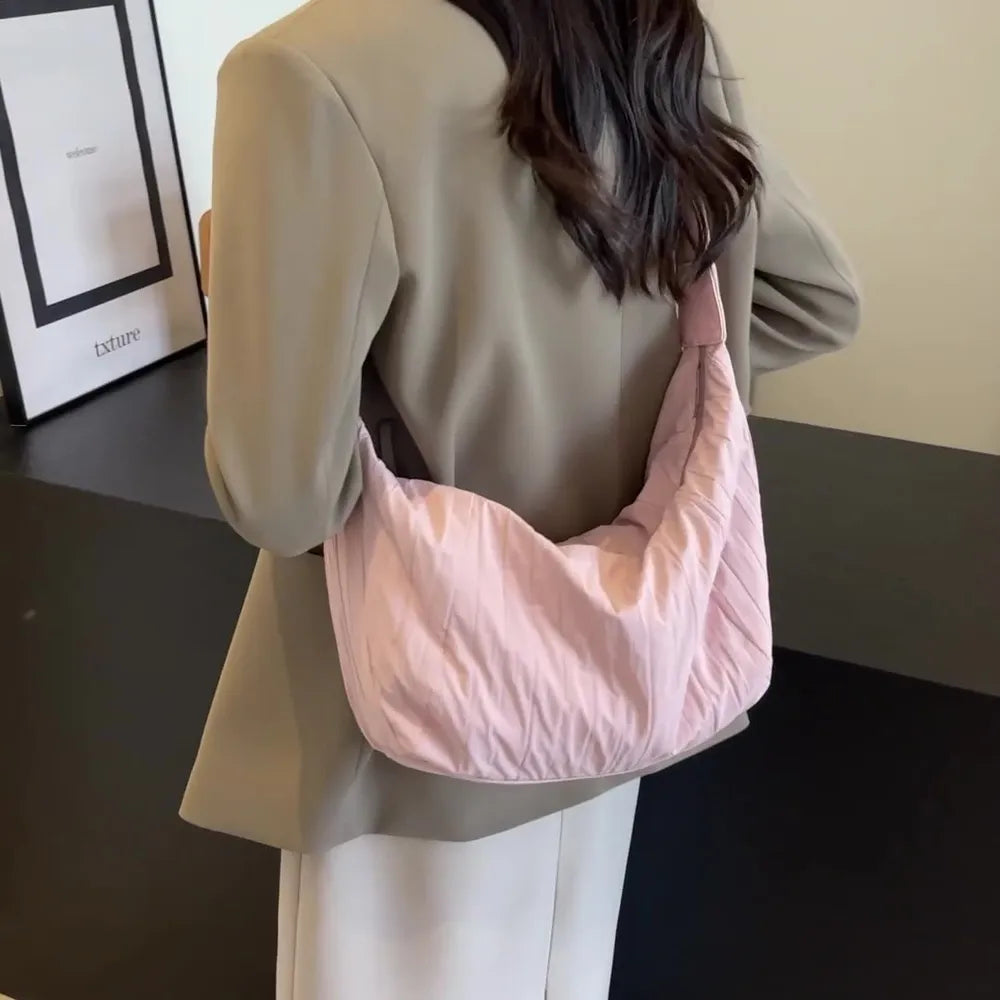 Pink quilted crescent shoulder bag with a soft, slouchy design.