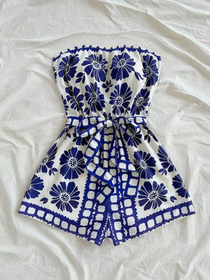 Blue floral tie-waist strapless romper with ruffled hem and tie detail.
