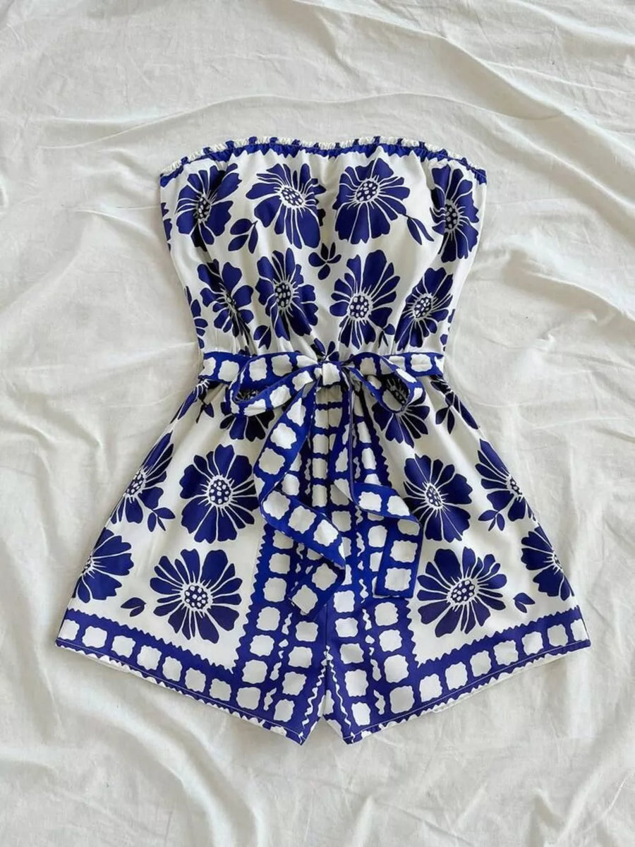 Blue floral tie-waist strapless romper with ruffled hem and tie detail.