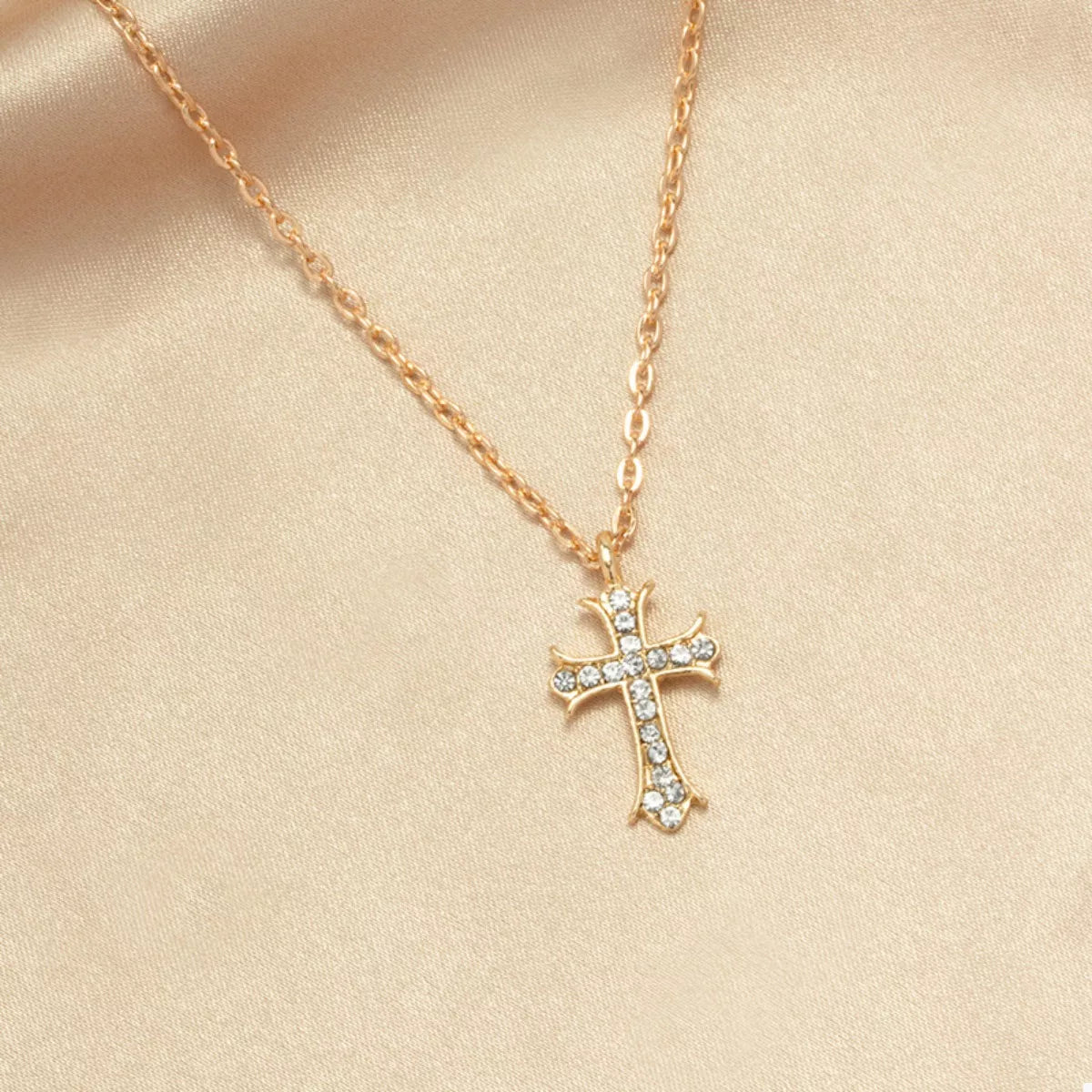 Gold rhinestone cross pendant necklace with delicate chain.