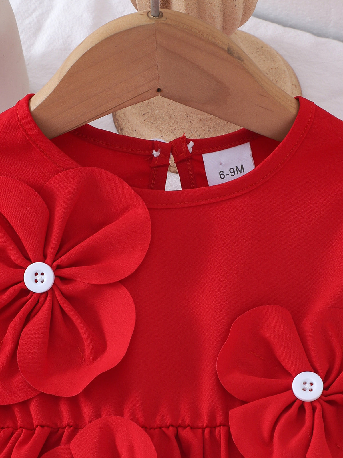 Red baby dress with flower appliqués and white buttons.