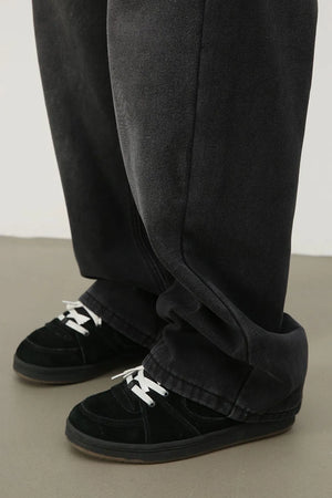 Oversized dark wash denim trousers with a relaxed fit, styled with black sneakers.