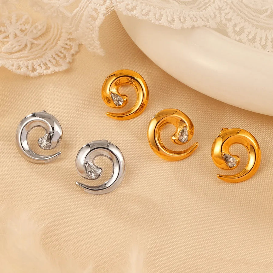 Sculptural zirconia swirl stud earrings in gold and silver with a unique spiral design.