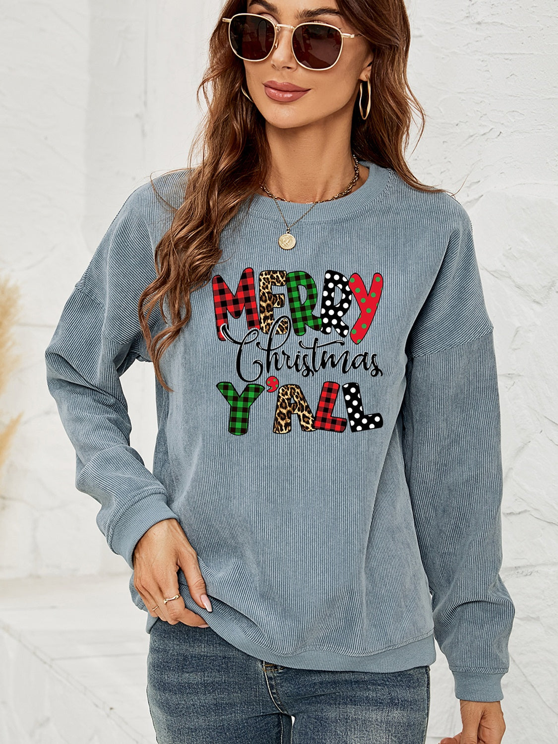 Light blue corduroy sweatshirt with Merry Christmas Y'all graphic in buffalo plaid, leopard, and polka dot patterns.