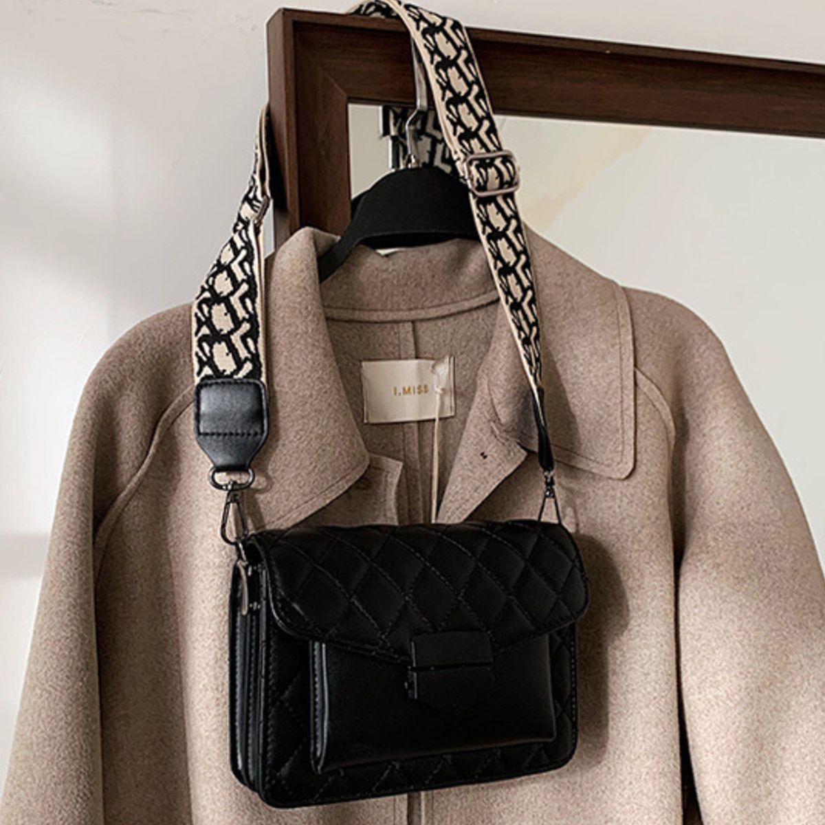 Black quilted flap crossbody bag with a patterned strap.