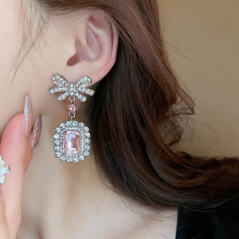 Silver bow crystal drop earrings with a pink gemstone pendant.