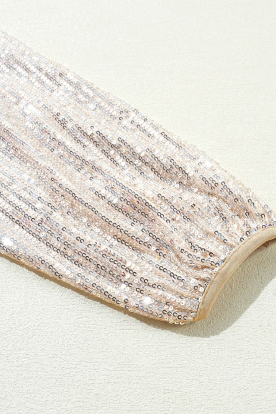 Sequin bomber jacket sleeve in cream with ribbed trim detail.