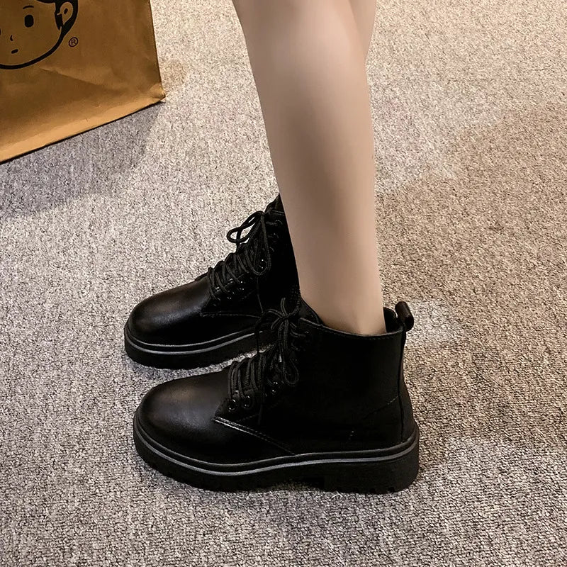 Black glossy leather combat booties with laces and side zip detail.