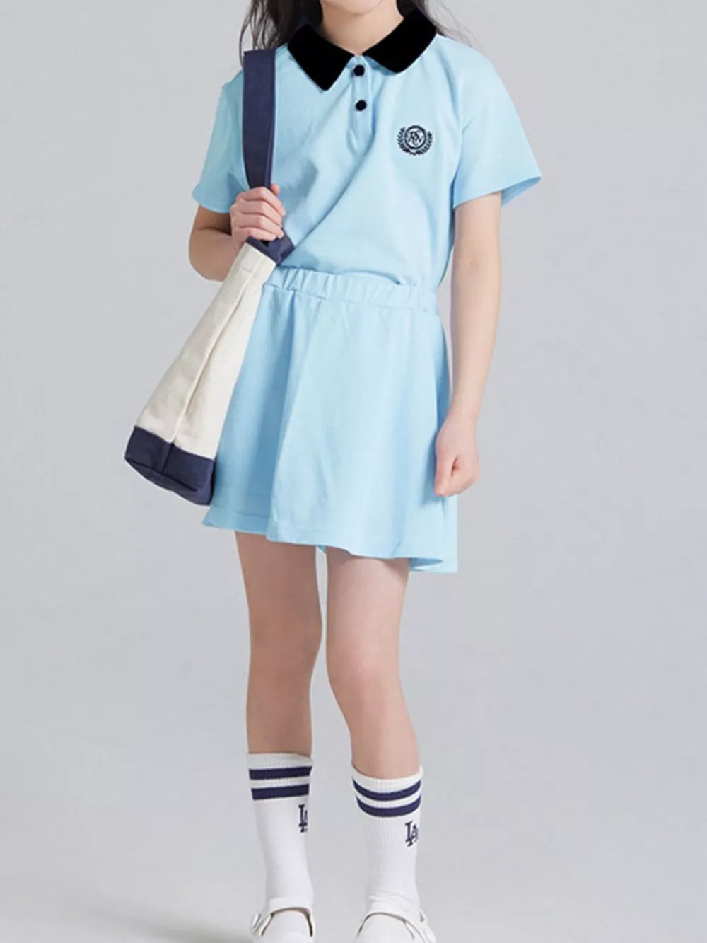 Light blue cotton polo skort ensemble for kids with black collar and embroidered crest.