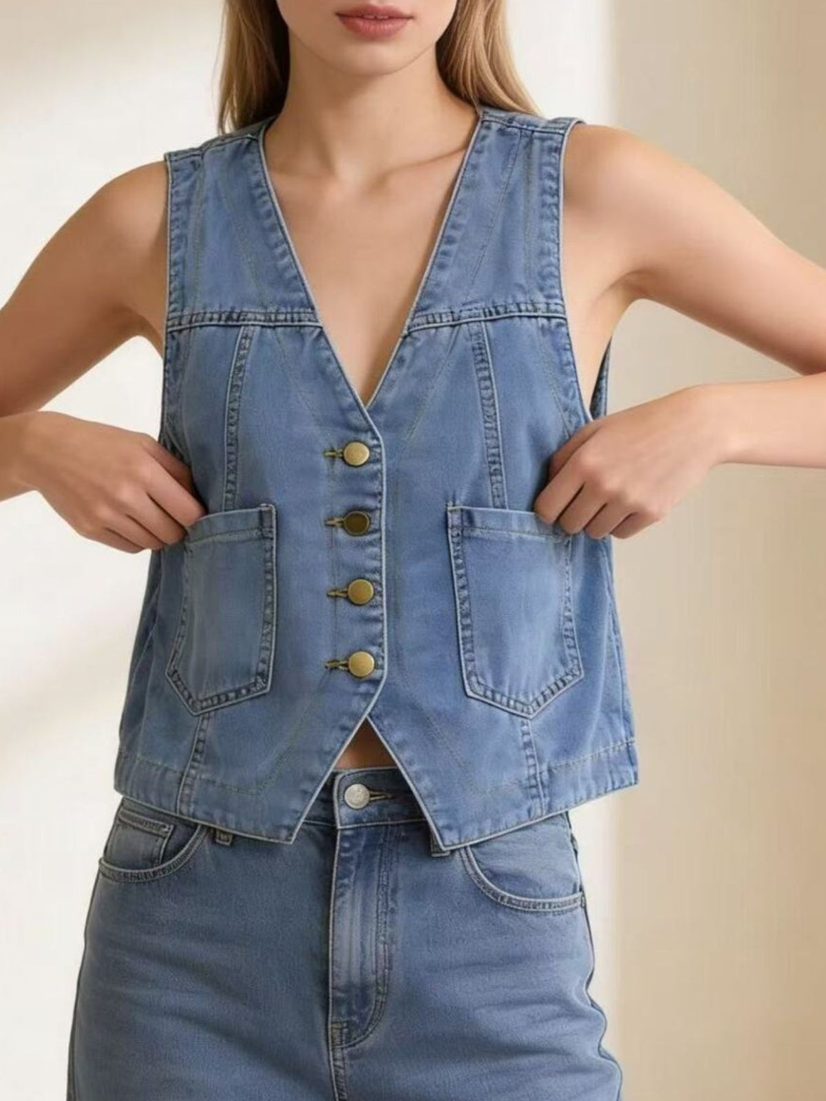 Light blue denim button-down vest with brass buttons and cropped length