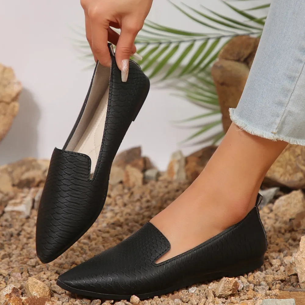 Black textured pointed-toe slip-on loafers with a subtle snakeskin pattern.