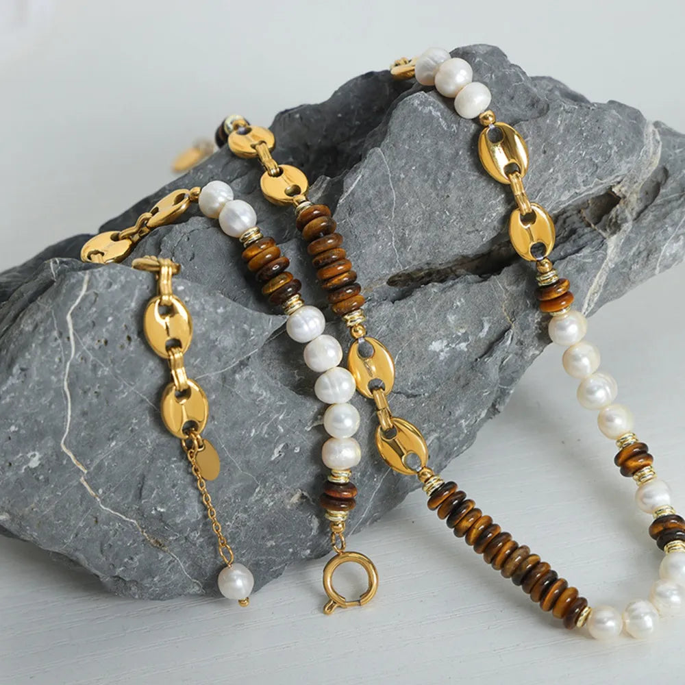 Gold pearl and tiger's eye link bracelet with oval chain links and a single pearl drop.