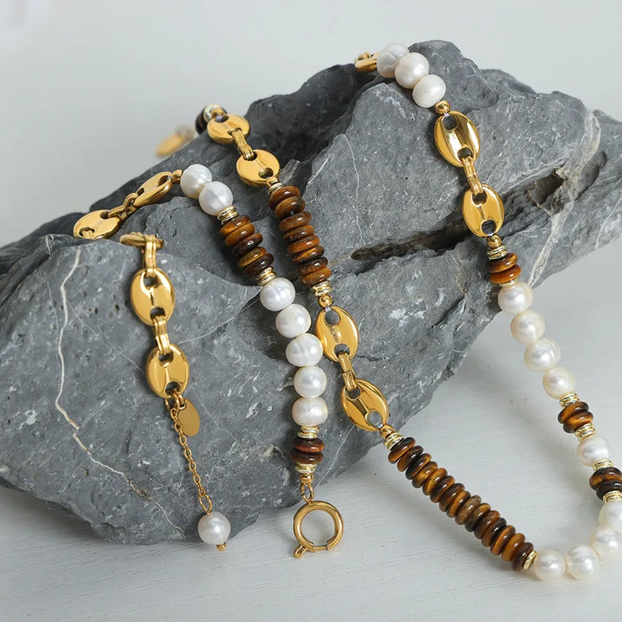 Gold pearl and tiger's eye link bracelet with oval chain links and a single pearl drop.