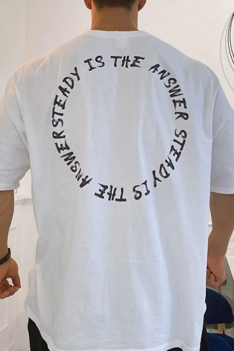 White oversized t-shirt with black circular text graphic on back
