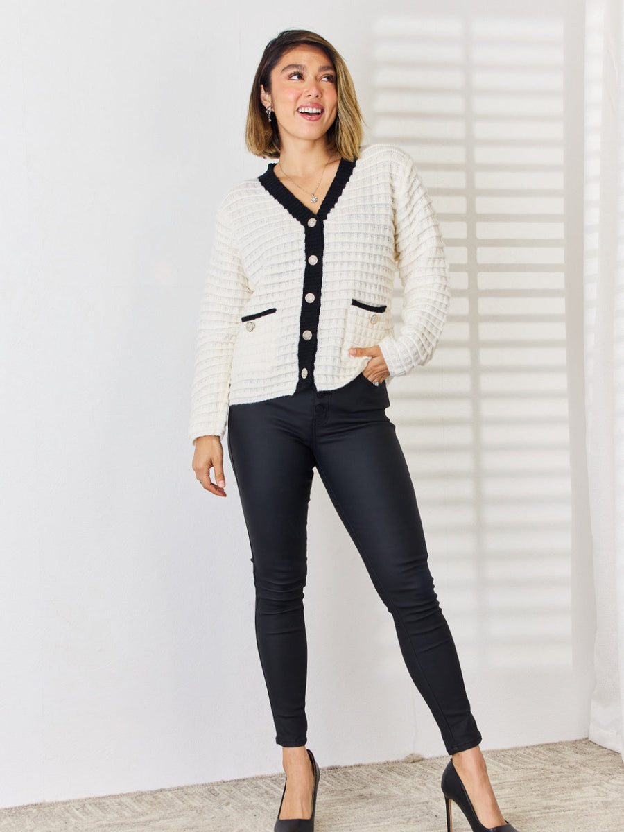 Textured knit white cardigan with black contrast trim and buttons.