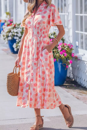 Pink polka dot midi dress with puff sleeves, smocked waist, and pockets.