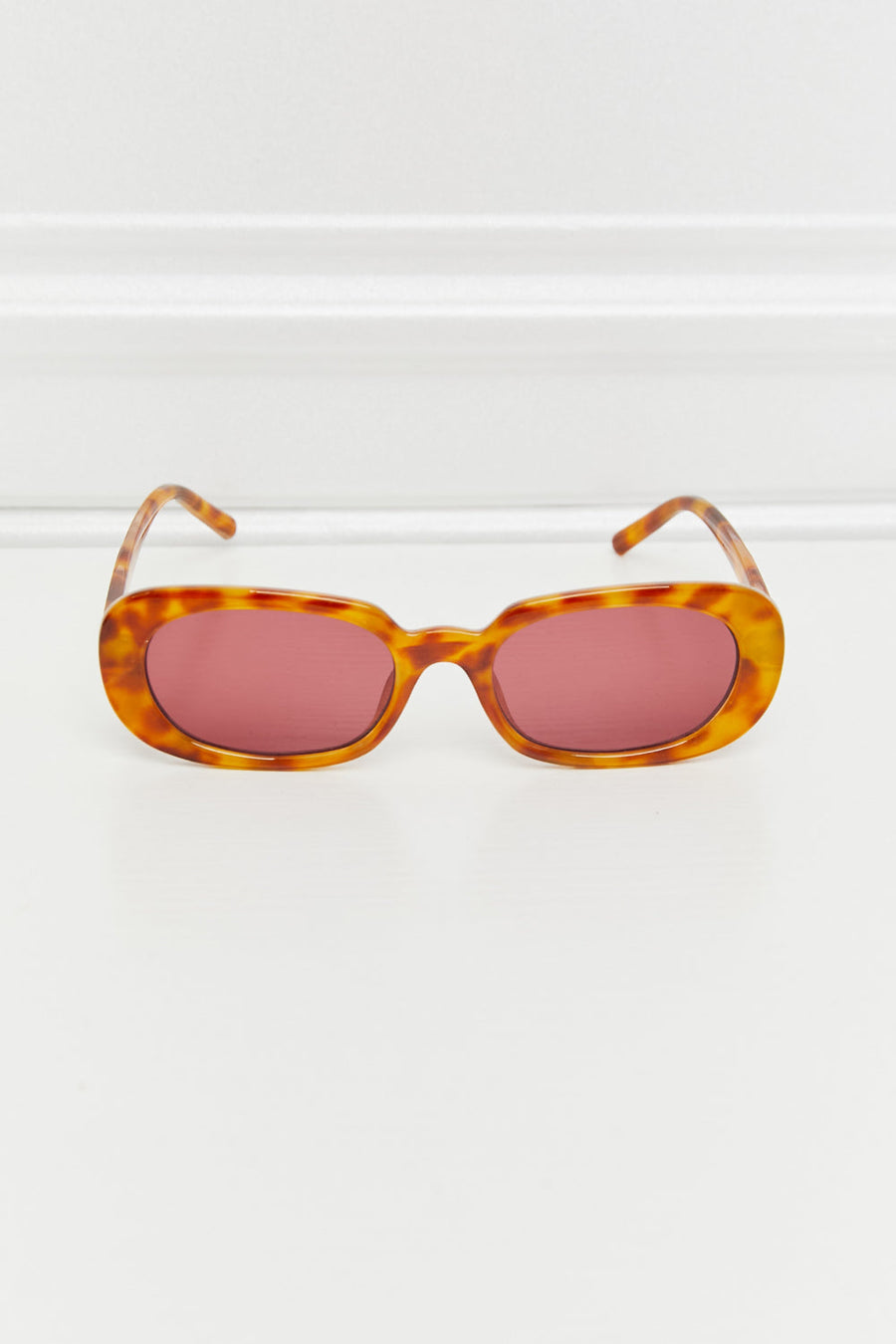 Tortoiseshell oval sunglasses with sunset lenses and brown frames.