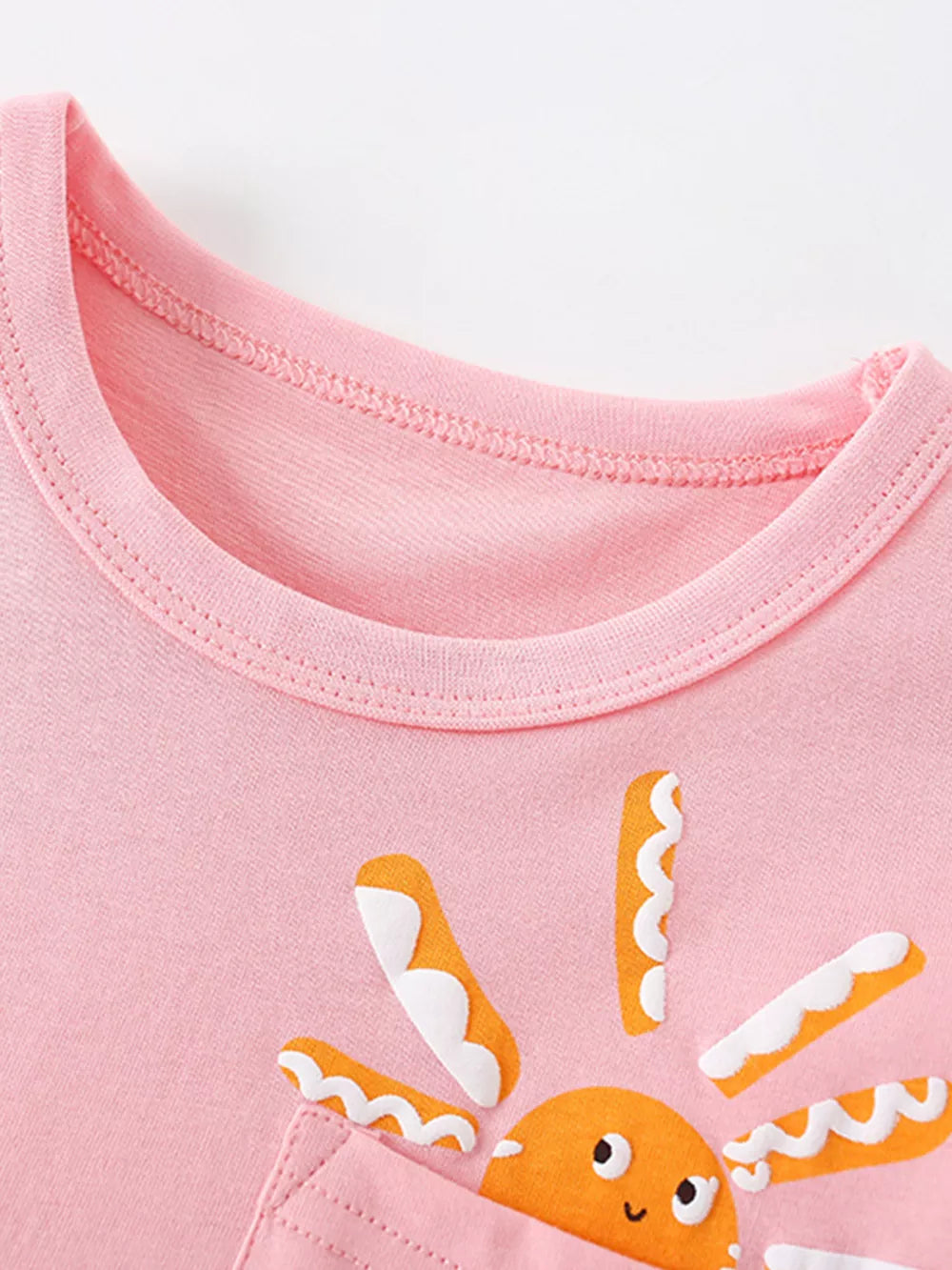 Pink cotton baby top with a smiling sun graphic and pocket detail.