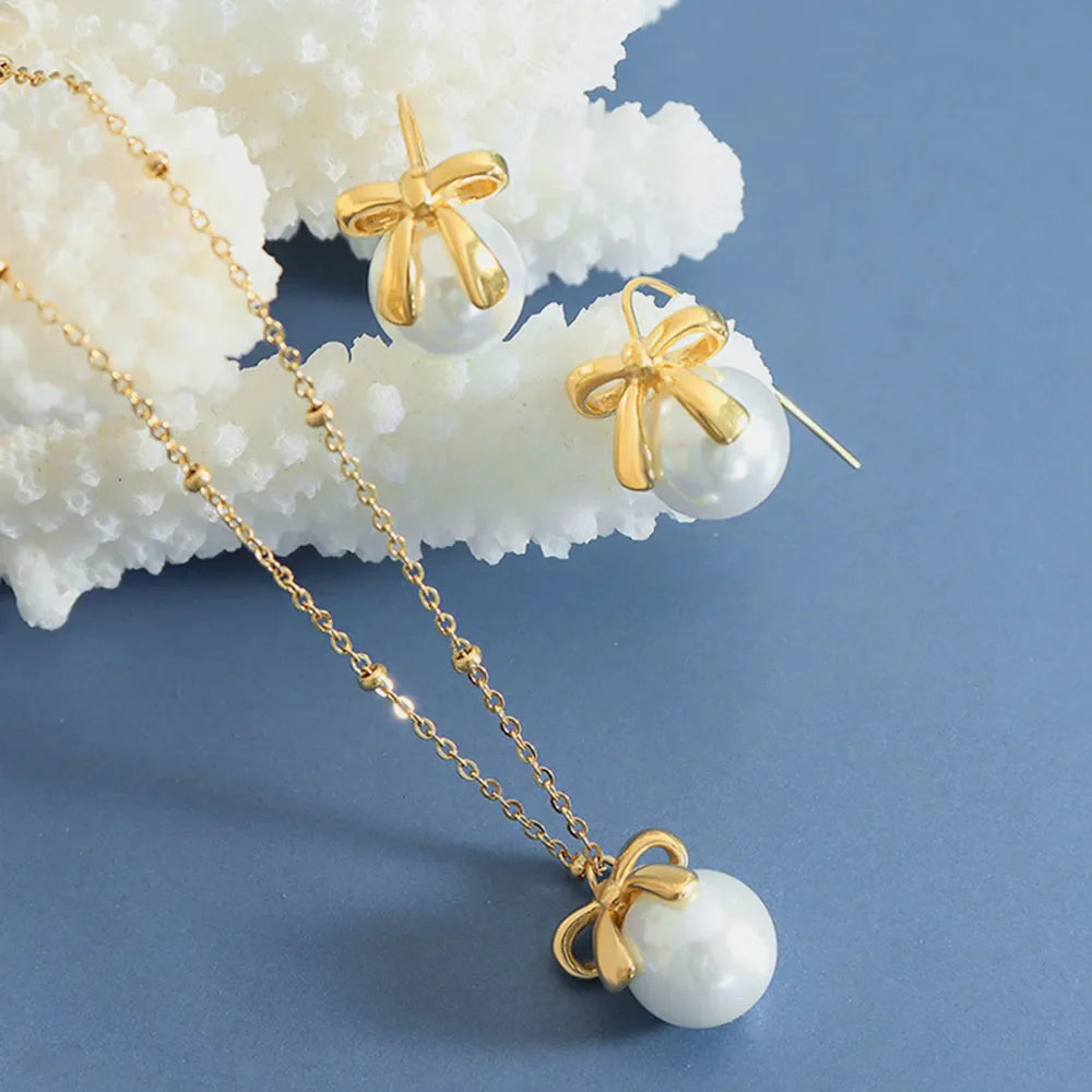 Gold bow pearl drop necklace and matching earrings with delicate bead chain.