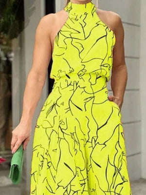 Canary yellow halter neck romper with abstract black print and wide legs.