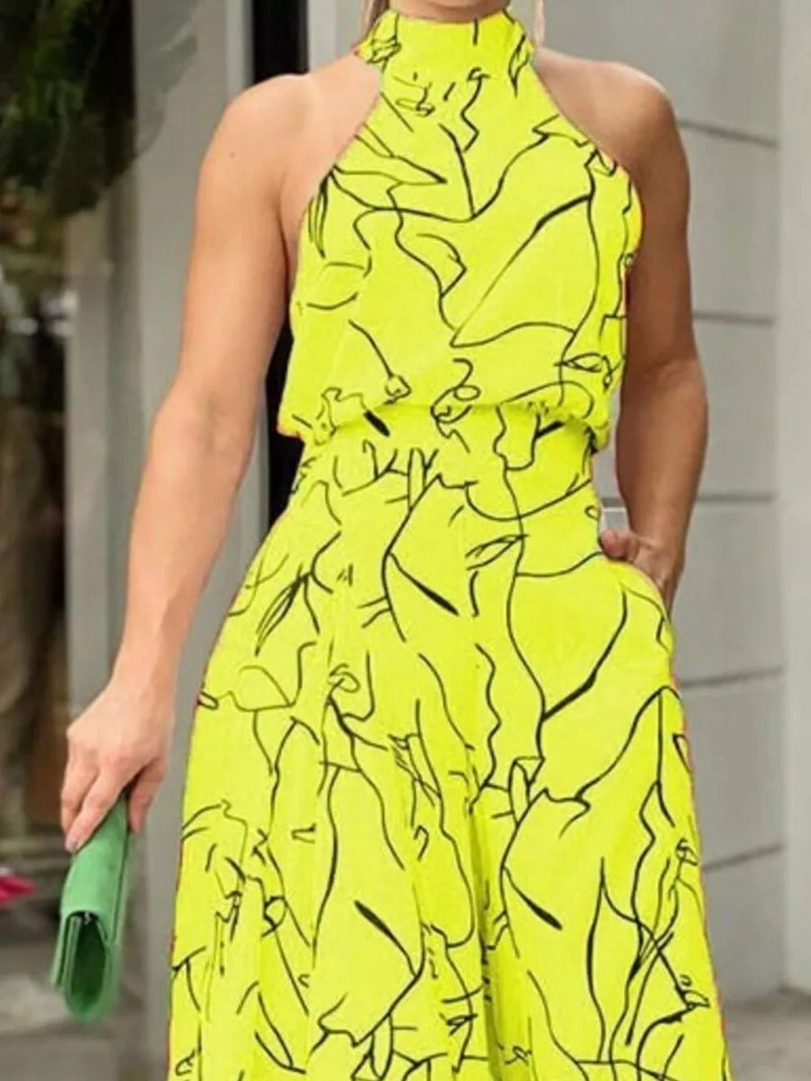 Canary yellow halter neck romper with abstract black print and wide legs.