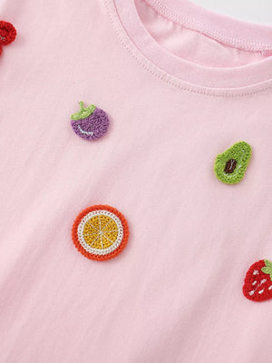 Pink cotton t-shirt with fruit appliques: strawberry, avocado, orange slice, and eggplant.