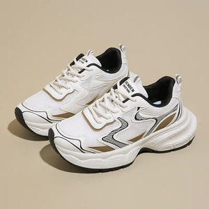 White mesh chunky trainers with black and gold accents.
