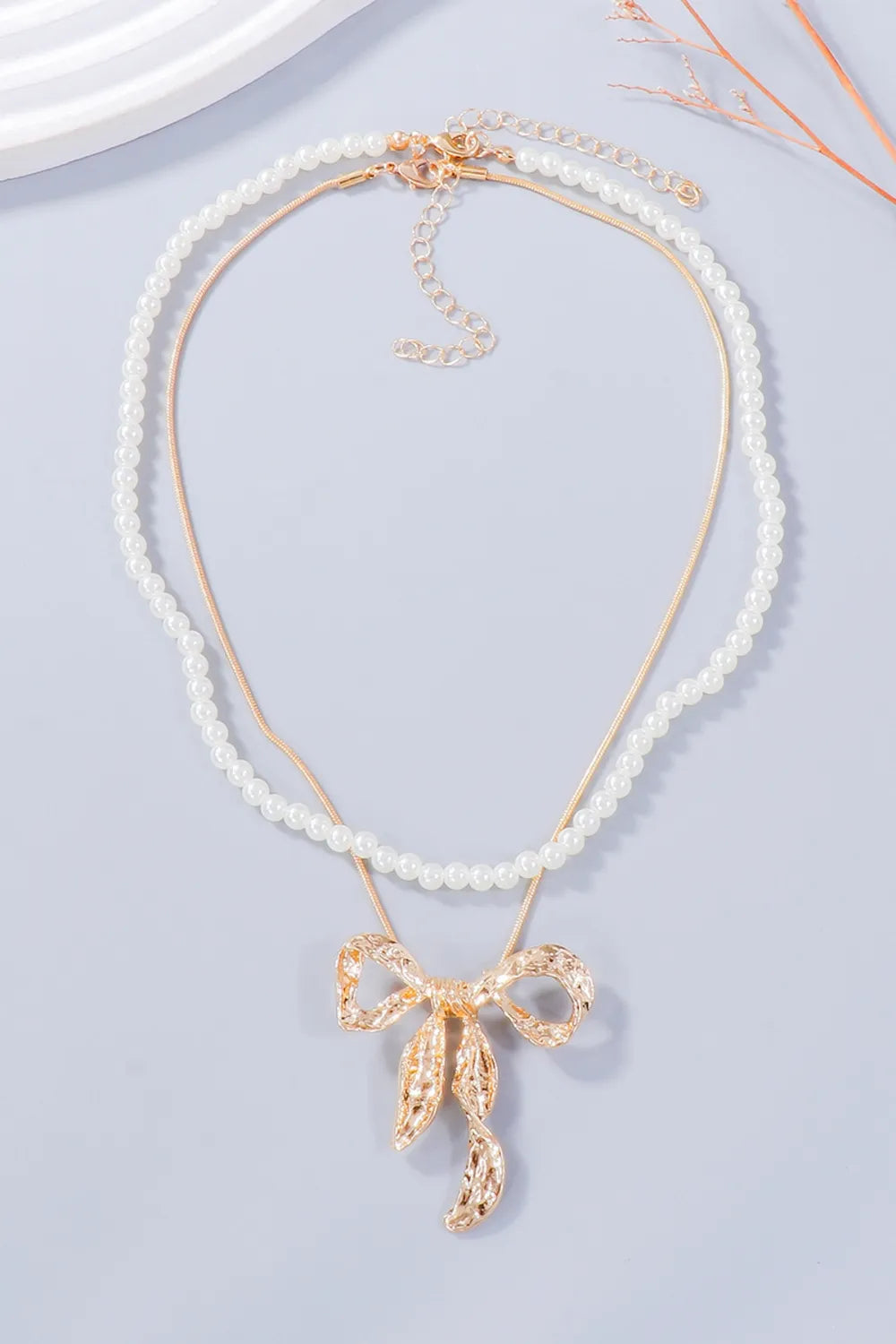 Gold jewelry set with pearl necklace and textured bow pendant