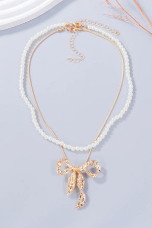 Gold jewelry set with pearl necklace and textured bow pendant