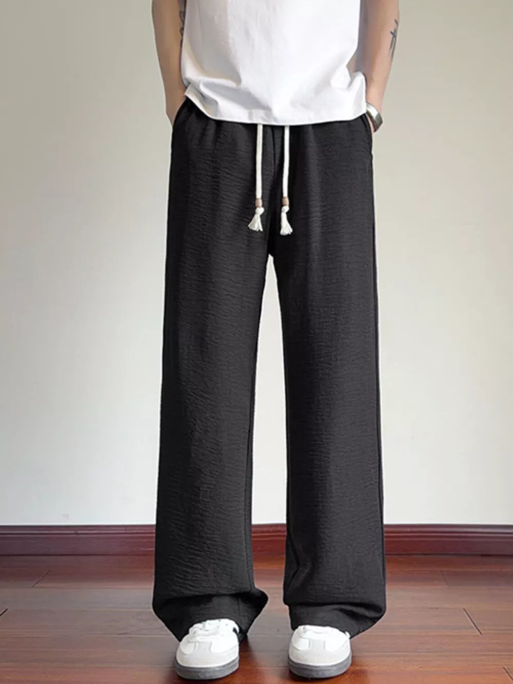 Black wide-leg drawstring sweatpants with textured fabric and tassel detail.