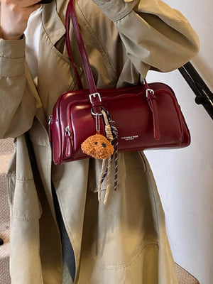 Deep red vintage leather shoulder bag with charm and fringe detail