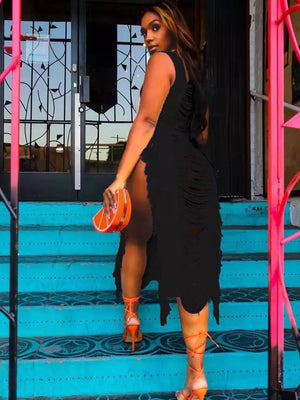 Black distressed fringe square neck midi dress with high slit, worn with orange lace-up heels.