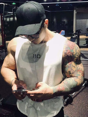 White athletic tank top with graphic detail, worn by a man with tattoos.
