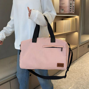 Pink nylon travel duffel bag with adjustable strap and front zip pocket.